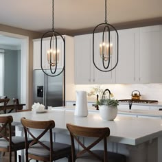 a kitchen island with chairs and lights hanging from it's ceiling over the counter