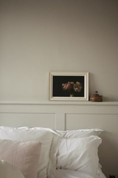 a bed with white sheets and pillows in a room