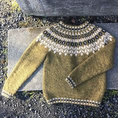 a green sweater sitting on top of a stone slab