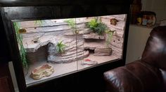 a living room with a large aquarium in the corner and a leather chair next to it