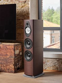 two speakers sitting next to each other in front of a tv on a wooden stand