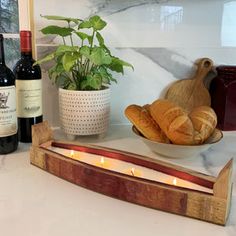 bread and wine are sitting on a counter next to a candle holder with two croissants in it