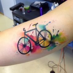 a watercolor painting style bicycle tattoo on the arm