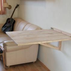 a living room with a couch, table and guitar hanging on the wall above it