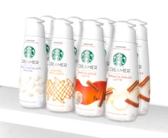 six starbucks coffee drinks are lined up on a shelf with cinnamons and other items