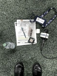 a person's shoes, camera, cell phone and other items laid out on the ground