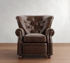 a brown leather chair sitting on top of a wooden floor