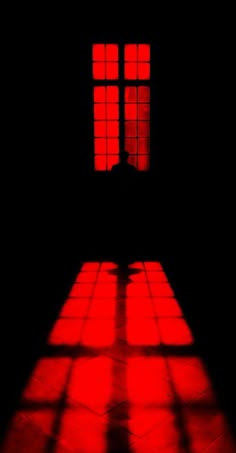 the shadow of a person standing in front of a window with red light coming through it