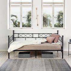 a day bed with two windows and a rug on the floor in front of it