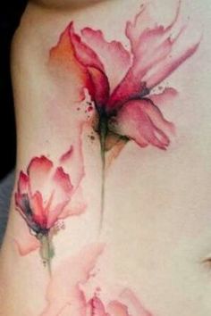 a woman's stomach with pink flowers tattooed on her side and the words watercolor tattoo