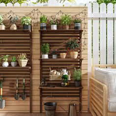 an outdoor garden area with potted plants and gardening tools on the shelves, in front of a wooden fence