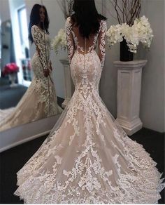 a woman in a wedding dress looking at herself in the mirror with her back to the camera