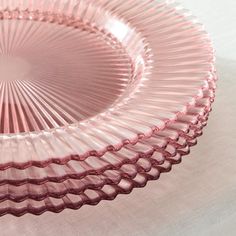 an empty pink glass plate sitting on a table