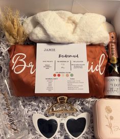 the contents of a bridesmaid gift box including sunglasses, champagne and other items