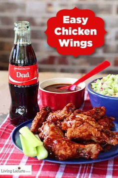 a blue plate topped with chicken wings next to a bowl of coleslaw and a bottle of soda