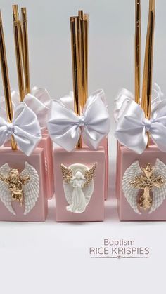 four little pink boxes with angel wings and gold sticks sticking out of the top one