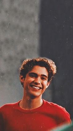 a smiling young man wearing a red shirt