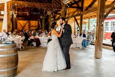 a bride and groom share their first dance at the wedding reception in an old barn