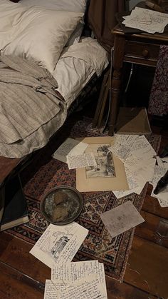 an unmade bed sitting on top of a wooden floor covered in papers and letters