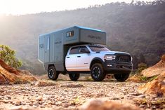 a white truck with a camper attached to it's bed in the mountains