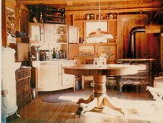 an old fashioned kitchen with wooden floors and cabinets in the corner, including a round dining table