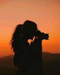 the silhouette of a woman holding a camera up to her face