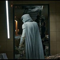 a man in a robe and hood is looking into a mirror