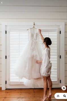 a woman is trying to hang her wedding dress