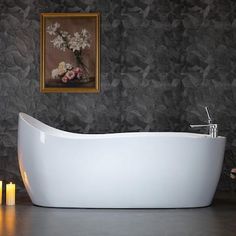 a white bath tub sitting on top of a bathroom floor next to candles and flowers