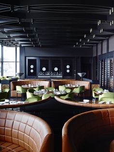 an empty restaurant with leather booths and green chairs in front of large windows that look out onto the city