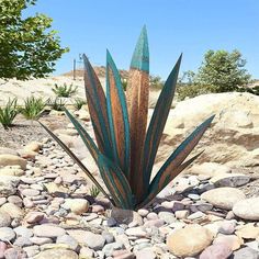 a metal plant sitting on top of a pile of rocks