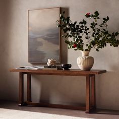 a vase with flowers on a table in front of a painting and other items sitting on the floor