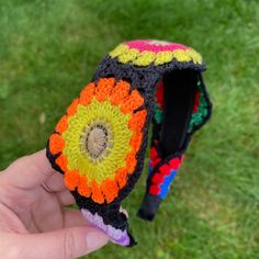 a hand holding a small crocheted object in it's left hand on the grass