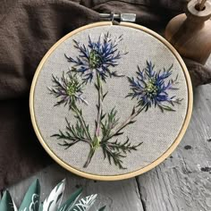 a cross - stitch pattern with blue flowers on it next to a potted plant