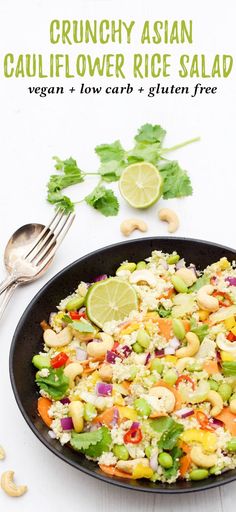 a bowl filled with rice and vegetables on top of a white table next to silverware