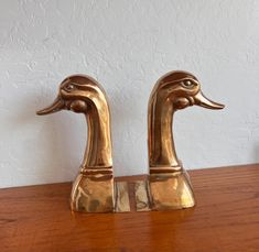 two brass ducks sitting on top of a wooden table