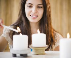 a woman sitting at a table with two candles in front of her