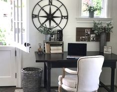 a desk with a laptop and chair in front of a large clock on the wall