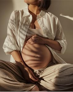 a pregnant woman sitting on the floor with her stomach exposed