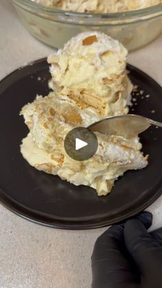 a black plate topped with food next to a bowl filled with ice cream and a knife