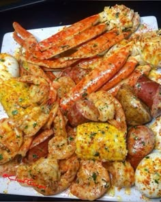 there is a white plate with shrimp and lobsters on it, as well as potatoes