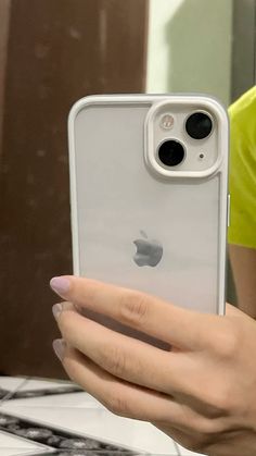 a woman holding an iphone in her hand and looking at the screen with both hands