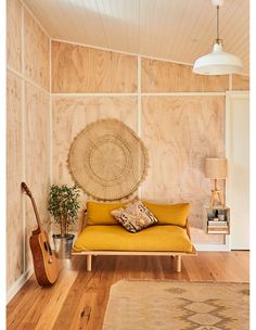 a living room with wood paneling and a yellow couch in front of a wooden wall