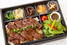 a bento box filled with meat, rice and vegetables next to dipping sauces