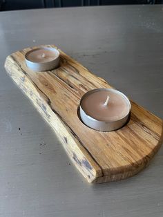 two candles sitting on top of a wooden tray