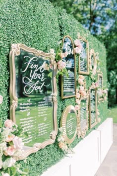 a wall covered in greenery with flowers and framed pictures on the side that says, find your seat