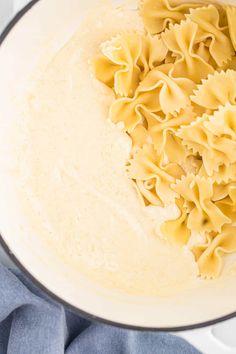 pasta being cooked in a pot on top of a blue towel with a wooden spoon