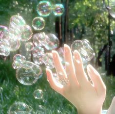 a person blowing soap bubbles in the air with their hands and fingers extended out to catch them