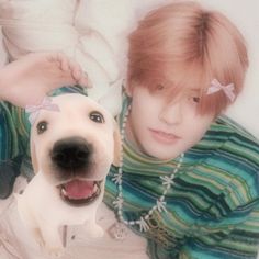 a young man laying next to a white dog