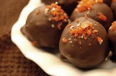 chocolate covered candies on a white plate with orange sprinkles